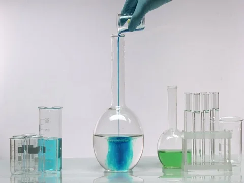Pouring blue solution in flask with transparent liquid Stock Footage 69780430