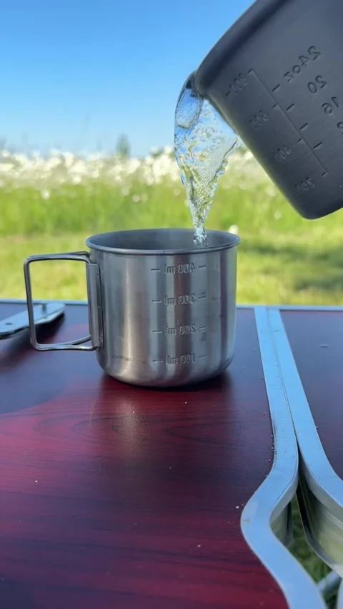 Pouring boiling water into a camping mug outdoors Stock Footage 310116667