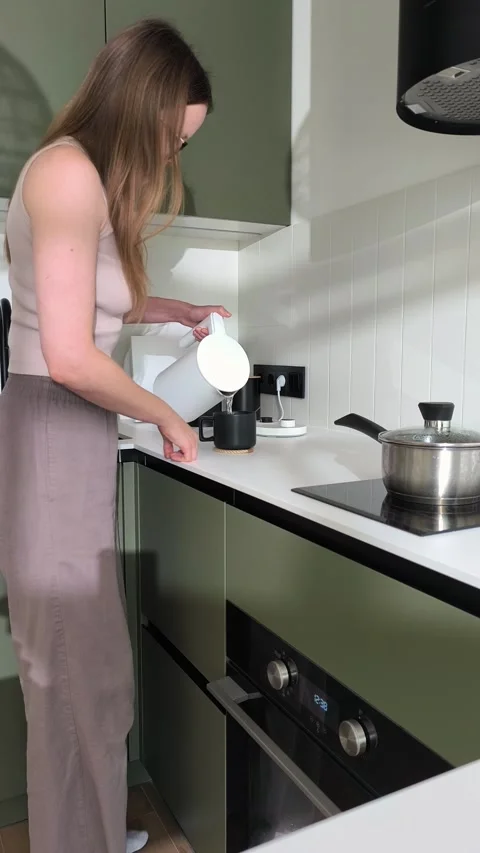Pouring boiling water from an electric kettle to brew hot tea in a cup. Cau.. Vidéo 346161363