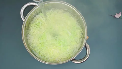 Pouring boiling water over shredded cabbage in indoor kitchen Stock Footage 342888942