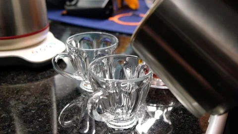 Pouring Brewed Tea and Hot Water into Glass Cups on Kitchen Countertop Stock Footage 302687080