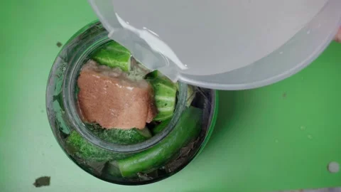 Pouring brine into a jar of cucumbers. View from above. Stock Footage 141317552