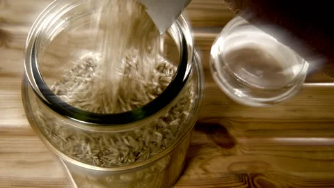 Pouring brown basmati rice from a packet into a storage jar. Stock-Footage 180870682