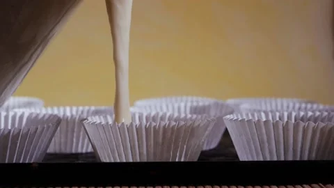 Pouring bun mixture into white bun cases ready for baking Stock Footage 170785904