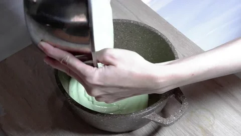 Pouring the cake batter from the cast iron pan into the metal bowl Stock Footage 236849362