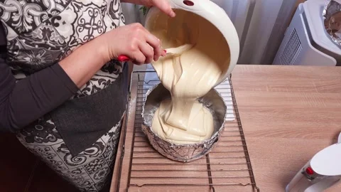 Pouring cake batter into a heart-shaped baking pan for dessert preparation Stock Footage 341935143