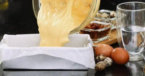 Pouring the cake batter into a rectangular shape covered with baking paper Stock Footage 151737937