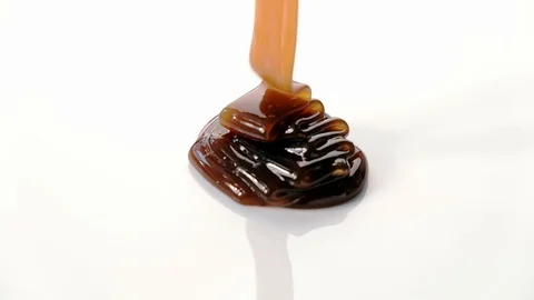 Pouring caramel syrup on white background Stock Footage 101489786