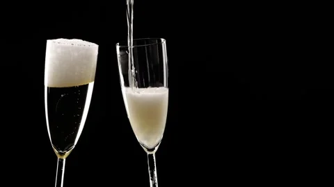 Pouring champagne into two glasses isolated on black Stock Footage 281166675