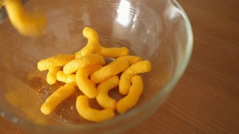 Pouring cheese crisps chips snacks into a bowl slow motion Stock Footage 159755618