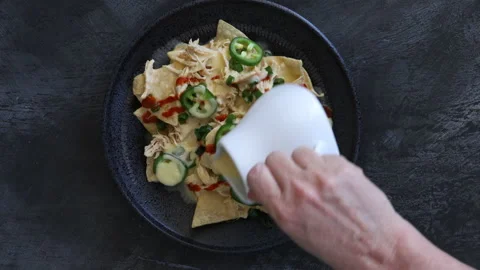 Pouring Cheese Sauce over Chicken Nachos shot from above Stock Footage 155490397
