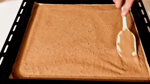 Pouring chocolate cake batter over christmas tree pattern on baking tray indoor Stock Footage 327259199