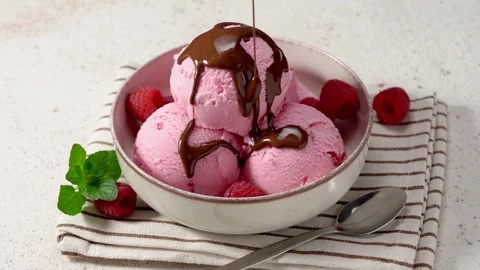 Pouring chocolate sauce over raspberry ice cream scoops 스톡 동영상 266587572