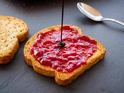  Pouring chocolate syrup on a slice of toast with raspberry jam Pouring ch... Stock Photos