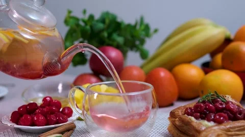 Pouring citrus tea in cup close-up. Fresh hot herbal tea with mint and oranges Video stock 310937345