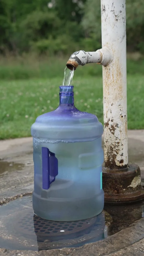 Pouring clean water into a large blue bottle outdoors Stock Footage 340835013