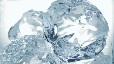 Pouring clear cold water into a glass with ice cubes. Slow motion Stock Footage