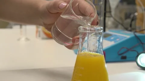 Pouring a clear liquid into a flask from a test tube- 库存影片 147908011