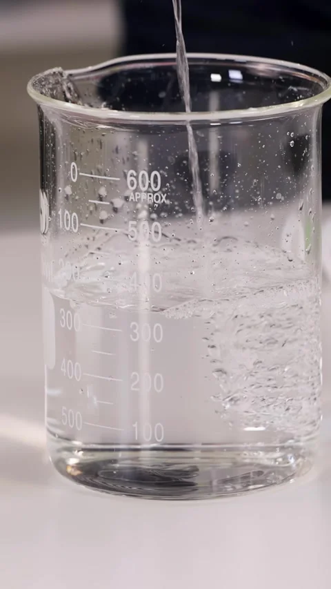 Pouring Clear Liquid into a Glass Beaker in a Laboratory Stock-Footage 344949164