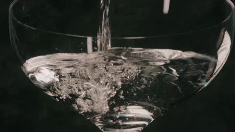 Pouring clear liquid over martini glass close up Stock Footage 339843244