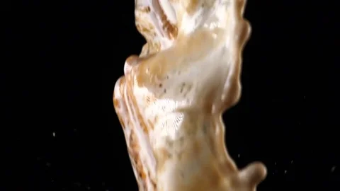 Pouring coffee and milk and making splashes on black background Stock Footage