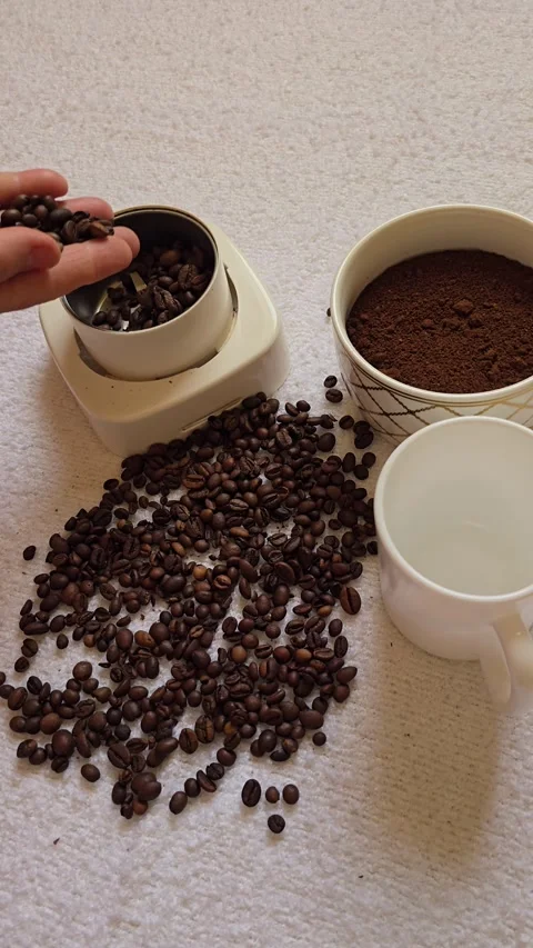 Pouring Coffee Beans into a Grinder with Ground Coffee in a Bowl. Stock Footage 341826859
