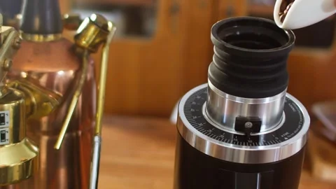 Pouring coffee beans into a modern single-dose coffee grinder, slow motion Stock Footage 343628464