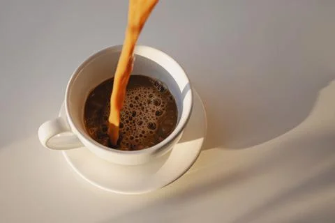 Pouring of coffee in a cup creating splash Foto stock