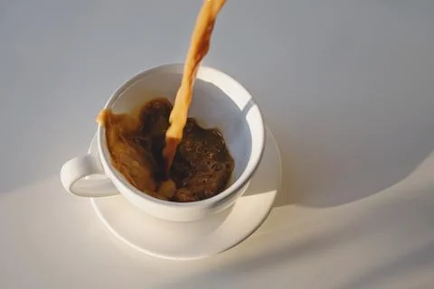 Pouring of coffee in a cup creating splash Stock Photos