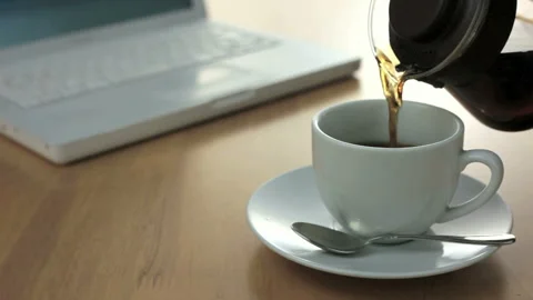 Pouring Coffee into a Cup in Front of the Computer 스톡 동영상 332508837