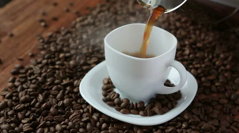 Pouring coffee in cup surrounded by coffee beans Stock Footage 61860338