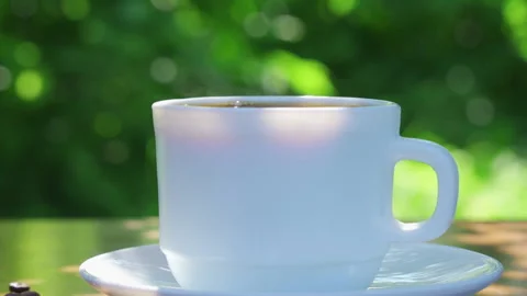Pouring coffee into a cup on a table in a garden landscape Stock Footage 201917262