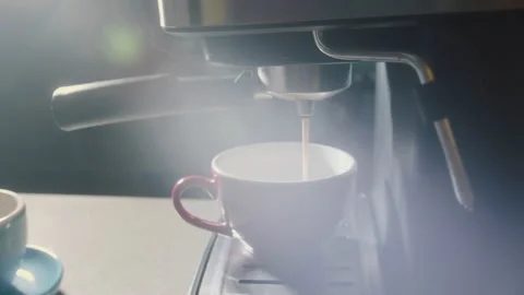 Pouring coffee stream from machine in red cup. Home making hot Espresso. Using Stock Footage 234310126