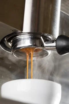 Pouring coffee stream from professional machine in cup. Barista making espresso Stock Photos