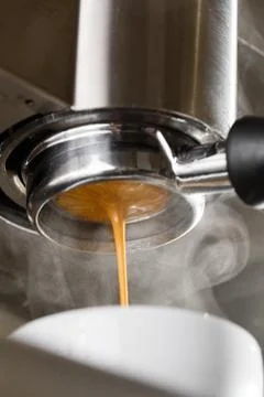 Pouring coffee stream from professional machine in cup. Barista making espresso Stock Photos