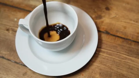 Pouring coffee into a white coffee cup on a wood table/ close up 스톡 동영상 130398997