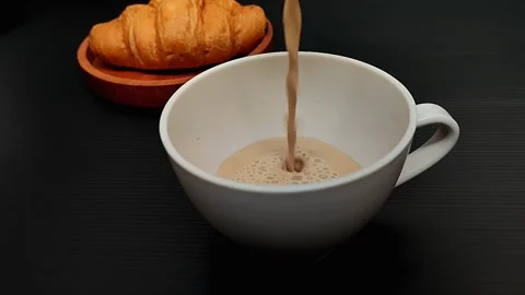 Pouring coffee into a white cup to complement the croisant Vídeo Stock 257785058