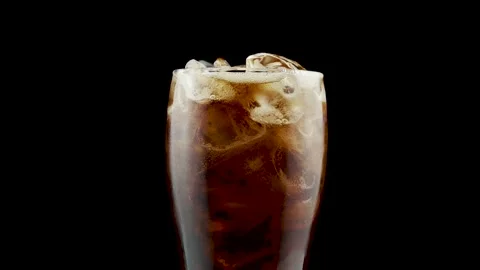 Pouring cola into glass with ice while rotating in a studio Stock Footage 233386595