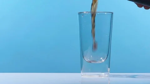Pouring cola into a glass on a table in a clean, studio environment. Shot in slo Stock Footage 74825635