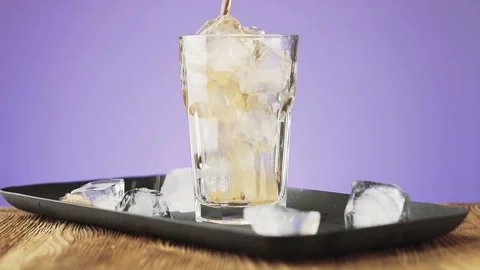 Pouring cola with ice cubes and bubbles in glass, slow motion. Stock Footage 92323191