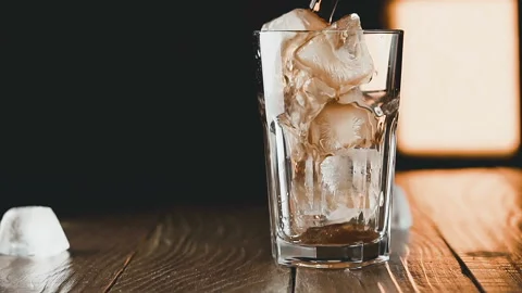 Pouring cola with ice cubes and bubbles in glass, slow motion. Stock Footage 93041432