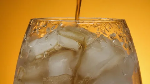 Pouring Cola with ice cubes close-up. Coke Soda closeup. Yellow Background. 4K U Video stock 132543666