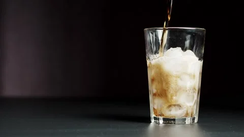 Pouring Cola with ice cubes close-up. Cola with Ice and bubbles in glass. Coke Stock-Footage 148169184
