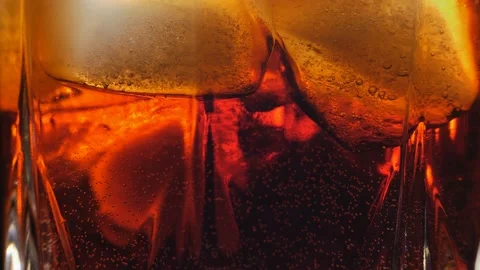 Pouring Cola with ice cubes close-up. Cola with Ice and bubbles in glass. Stock Footage 155245318