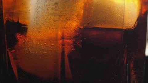 Pouring Cola with ice cubes close-up. Cola with Ice and bubbles in glass. Stock Footage 160769098