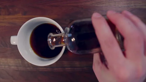 Pouring cold brew coffee into coffee cup overhead view Stock Footage 130404386