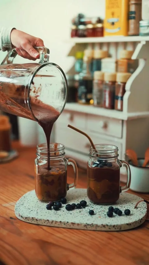 Pouring Cold Brew Coffee into Glass Jars in a Cozy Cafe Setting Video stock 343906602
