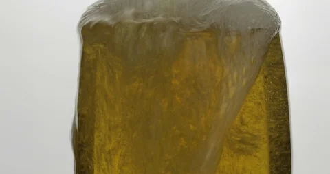 Pouring cold golden light beer into a glass. Craft beer making bubbles and foam Stock Footage 106565863