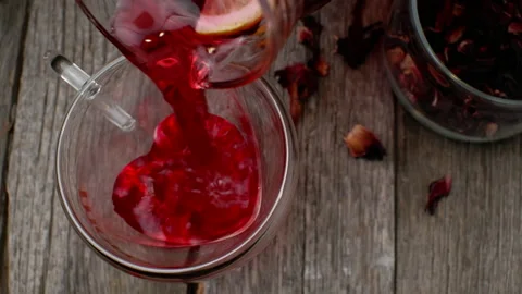 Pouring cold red tea with lemon to a heart shaped glass cup. View from above. Stock Footage 155816210