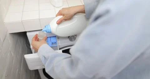 Pouring conditioner into a washing machine Stock Footage 150622411